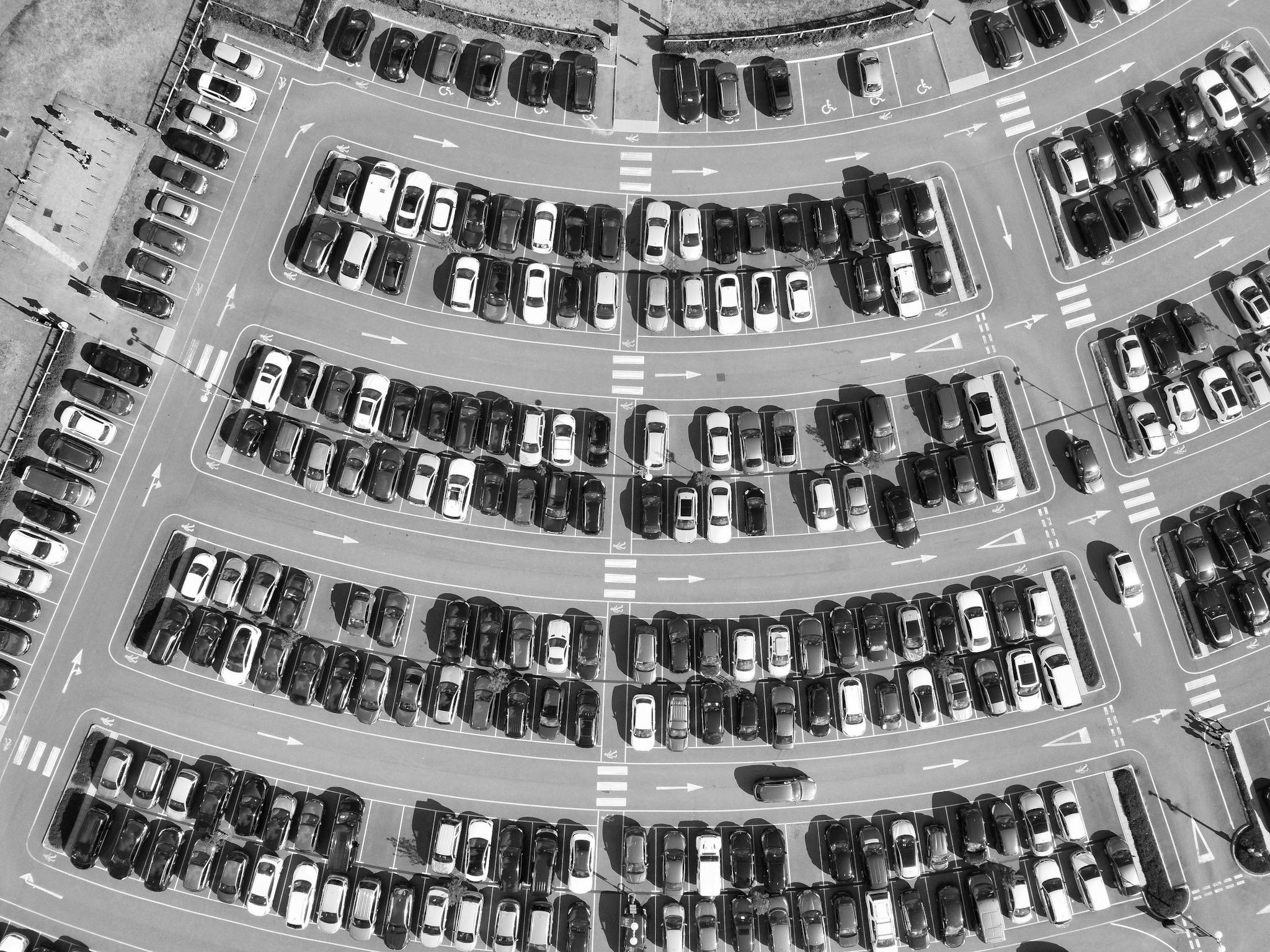 High-angle black and white shot of a crowded parking lot in England, showcasing numerous vehicles.